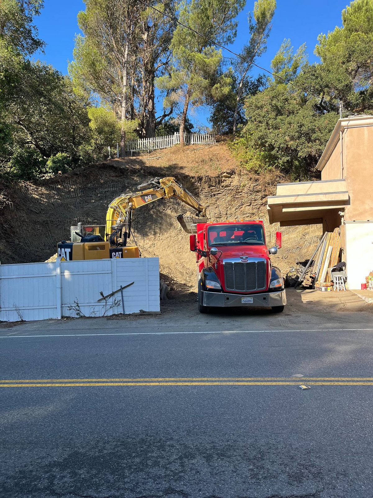 Excavator and dump truck working on a Southern California hillside construction site
