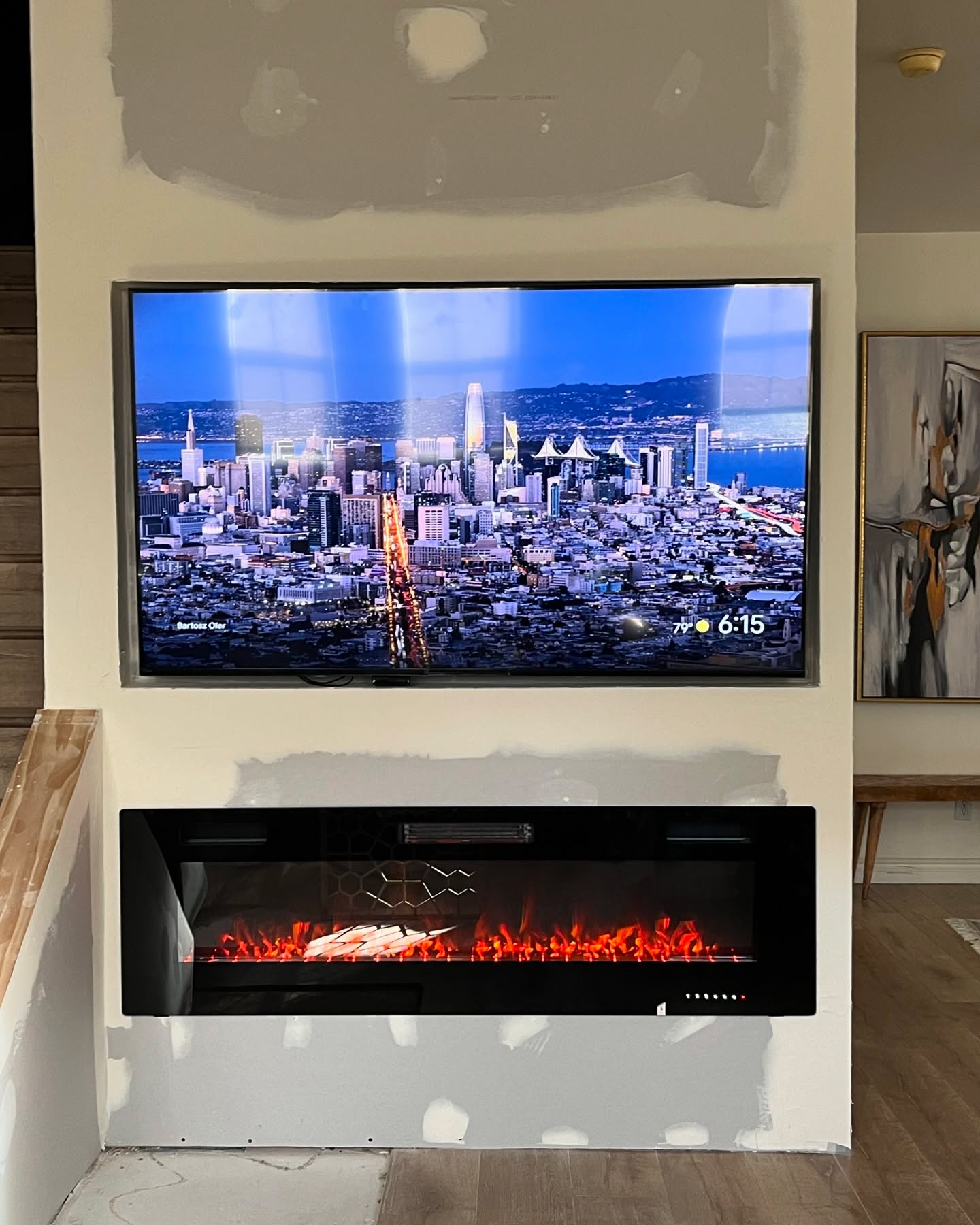 Custom media wall with mounted television and electric fireplace during finishing work